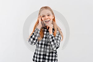 Portrait of smiling modern teen girl talking on mobile phone, thinking while on call, standing over white background