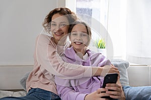 Portrait of smiling mom and teen daughter relax at home