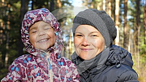Portrait of smiling mother and daughter in the autumn forest.