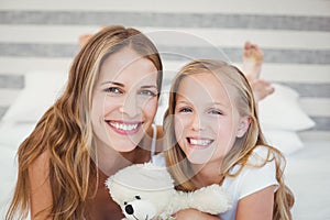 Portrait of smiling mother and daughter on bed at home