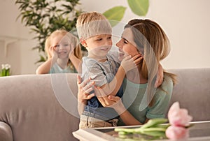 Portrait of smiling mother and her cute little children at home