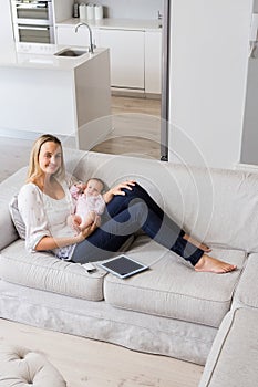 Portrait of smiling mother sitting with her baby in living room