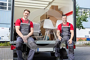 Portrait Of Smiling Movers Sitting In Truck With Moving Boxes