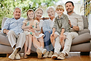 Portrait of a smiling multi generation caucasian family sitting close together on the sofa at home. Happy adorable