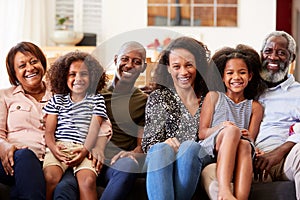 Portrait Of Smiling Multi-Generation Family Sitting On Sofa At Home Relaxing Together