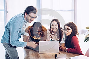 portrait of smiling multicultural business people working on laptop together