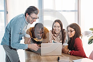 portrait of smiling multicultural business people working on laptop together photo