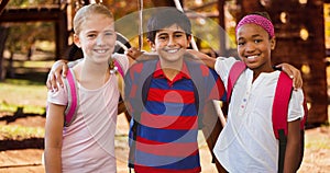 Portrait of smiling multiracial girls and boy with arm around standing at park