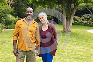 Portrait of smiling multiracial senior couple spending leisure time together in backyard