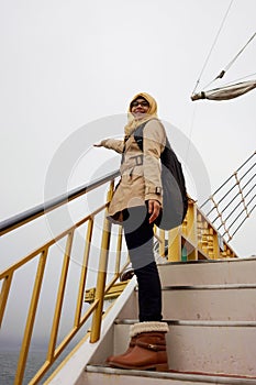 Portrait of smiling muslim woman on board sightseeing cruise ship at Lake Ashi with waving hands gesture and happy expression