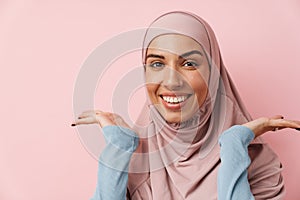 A portrait of the smiling muslim woman wearing pink hijab spreading her arms to the sides
