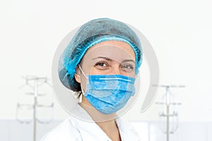 Portrait of a smiling nurse in a protective cap and mask