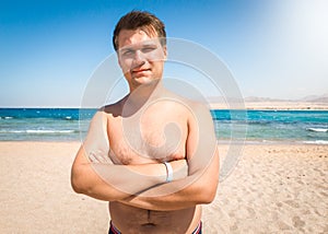 Portrait of smiling obese man with excess weight posing on the sea beach and looking in camera