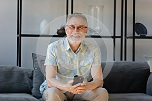 Portrait of smiling old man with cellphone in hands.