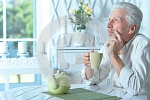 Portrait of smiling old man drinking tea at home