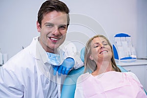 Portrait of smiling patient and dentist sitting on chair