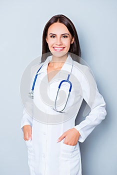 Portrait of smiling pediatricion holding hands in pockets of uniform
