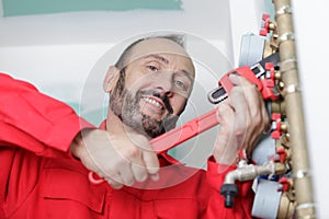 portrait smiling plumber using wrench on pipework photo