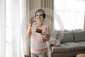 Portrait of smiling pregnant woman eating chocolate cake at home