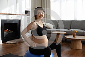 Portrait of smiling pregnant woman sitting on fit ball