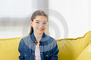 portrait of smiling preteen child looking at camera on sofa