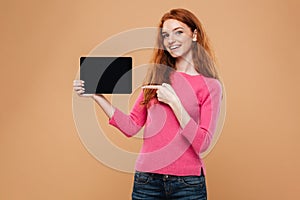 Portrait of a smiling pretty redhead girl pointing finger