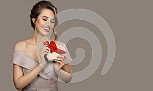 Portrait of smiling pretty woman holding a gift box heart in hands.