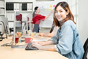 Portrait of smiling pretty young business asian woman working on computer