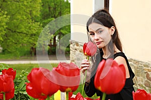 Portrait of smiling pretty young teen girl among red tulips