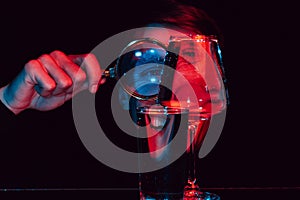 portrait of a smiling psychopath man looking through a magnifying glass and glass glasses