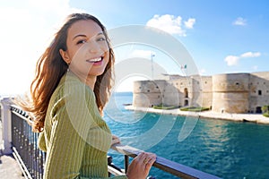 Portrait of smiling relaxed woman looking at camera with Taranto seafront on the background, Apulia, Italy photo