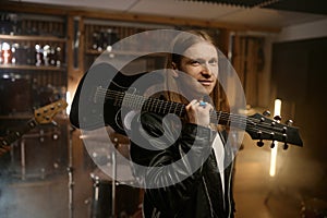 Portrait of smiling rock guitarist carrying music instrument on shoulder