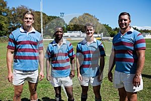 Portrait of smiling rugby team standing on grassy field