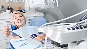 Satisfied woman visiting dentist giving thumbs up