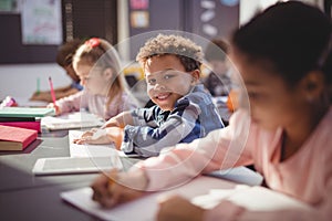 Portrait of smiling schoolboy doing his homework in classroom