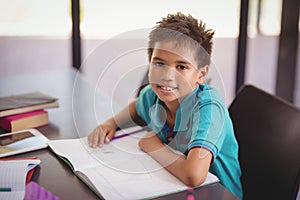 Portrait of smiling schoolboy doing his homework in library