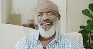 Portrait of smiling senior african american man looking at camera in living room
