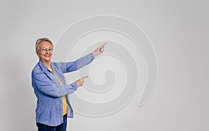 Portrait of smiling senior businesswoman pointing at copy space and marketing on white background