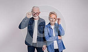 Portrait of smiling senior couple looking out through eyeglasses while standing on white background