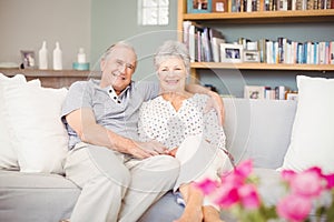 Portrait of smiling senior couple sitting on sofa in living room