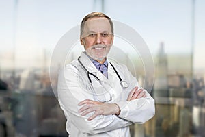 Portrait of smiling senior doctor with folded arms.