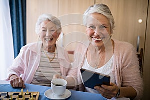 Portrait of smiling senior friends having coffee while playing chess