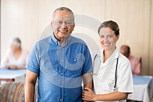 Portrait of smiling senior male patient with female doctor