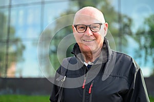 Portrait of a smiling senior man in front of a modern building