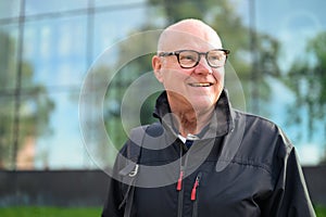 Portrait of a smiling senior man in front of a modern building thinking