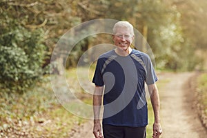 Portrait Of Smiling Senior Man Running In Autumn Countryside Exercising During Covid 19 Lockdown