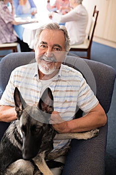 Portrait of smiling senior man sitting with puppy on armchair