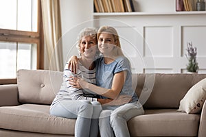 Portrait of smiling senior mom and adult daughter hugging