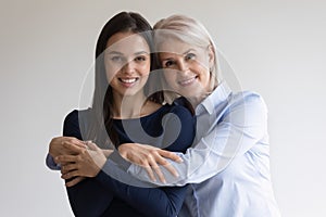 Portrait of smiling senior mother and adult daughter hugging
