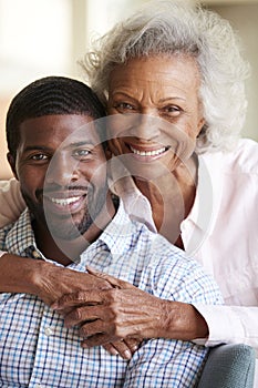 Portrait Of Smiling Senior Mother Hugging Adult Son At Home photo